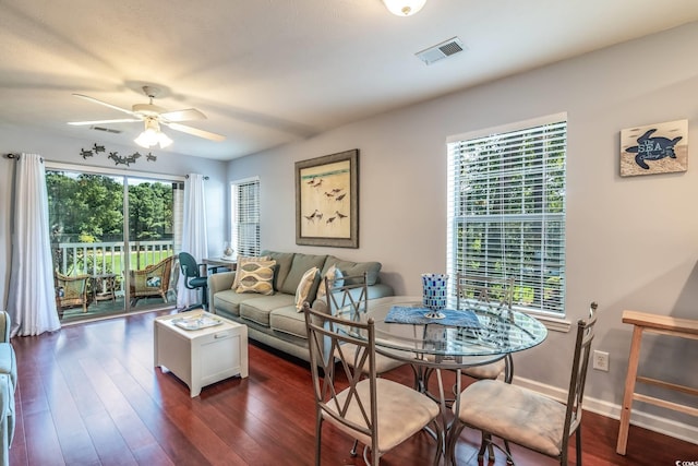 living room with a wealth of natural light, ceiling fan, and dark wood-type flooring