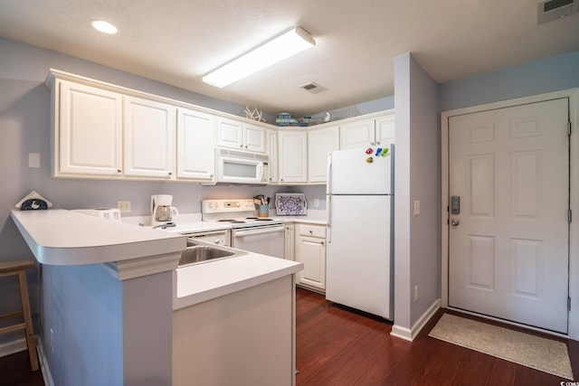 kitchen with kitchen peninsula, white appliances, white cabinets, and dark hardwood / wood-style floors