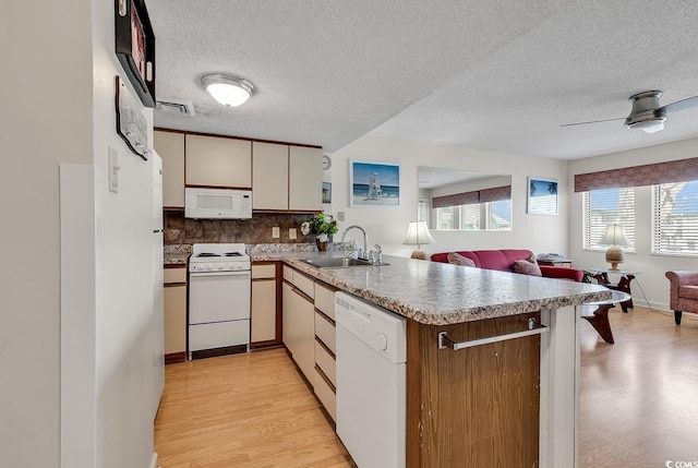 kitchen with kitchen peninsula, tasteful backsplash, white appliances, ceiling fan, and sink