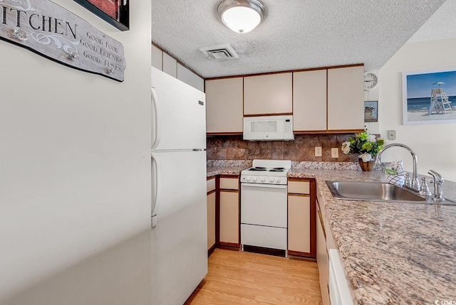 kitchen featuring light wood-type flooring, a textured ceiling, white appliances, sink, and white cabinetry