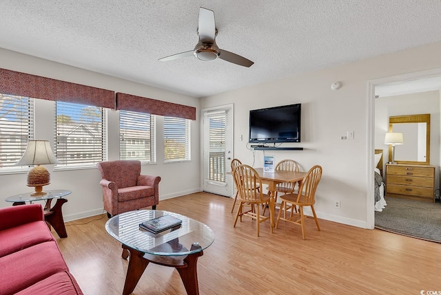 living room with a textured ceiling, light wood-type flooring, and ceiling fan