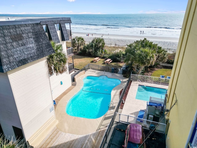 view of pool with a patio area, a water view, and a beach view