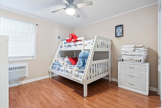 bedroom with wood-type flooring, a textured ceiling, an AC wall unit, and ceiling fan