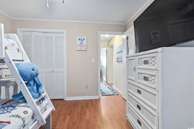 bedroom featuring hardwood / wood-style floors, a textured ceiling, a closet, and ornamental molding