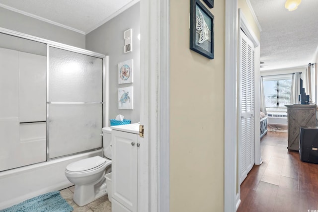 full bathroom with combined bath / shower with glass door, wood-type flooring, a textured ceiling, toilet, and vanity