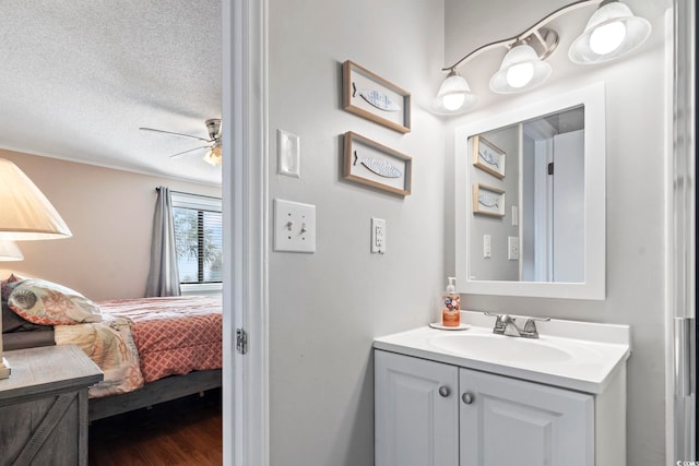 bathroom with ceiling fan, vanity, and a textured ceiling