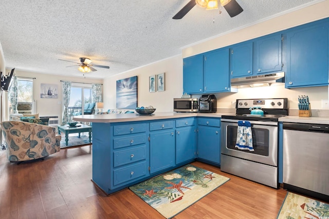 kitchen with kitchen peninsula, a textured ceiling, stainless steel appliances, and blue cabinets