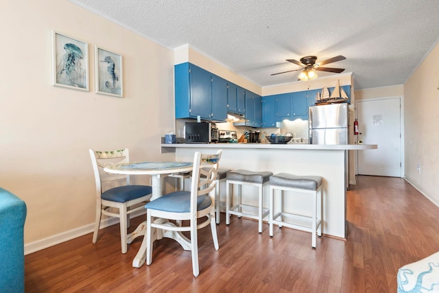 kitchen with a textured ceiling, a kitchen breakfast bar, kitchen peninsula, and blue cabinets