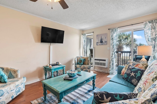 living room featuring a wall mounted air conditioner, hardwood / wood-style floors, a textured ceiling, and ceiling fan