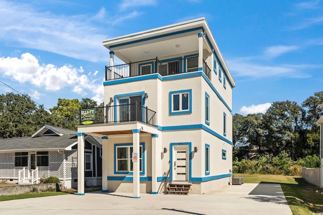 view of front of home with central AC unit and a balcony