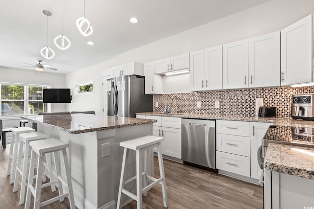 kitchen featuring a kitchen breakfast bar, decorative light fixtures, a kitchen island, white cabinetry, and stainless steel appliances