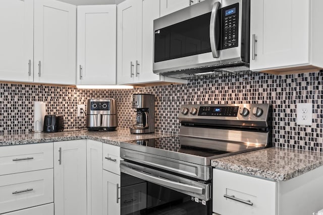 kitchen featuring light stone countertops, appliances with stainless steel finishes, backsplash, and white cabinetry