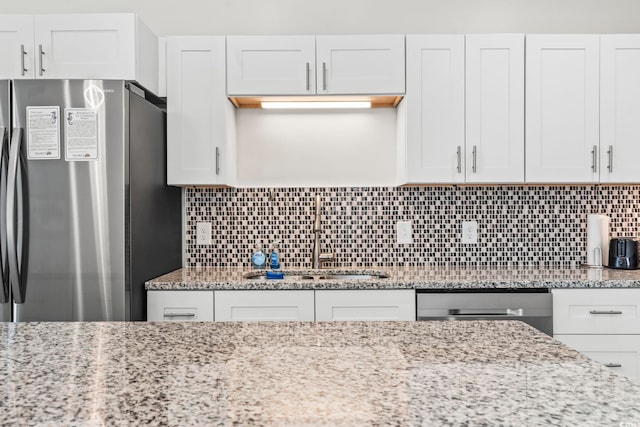 kitchen with white cabinets, backsplash, sink, and appliances with stainless steel finishes