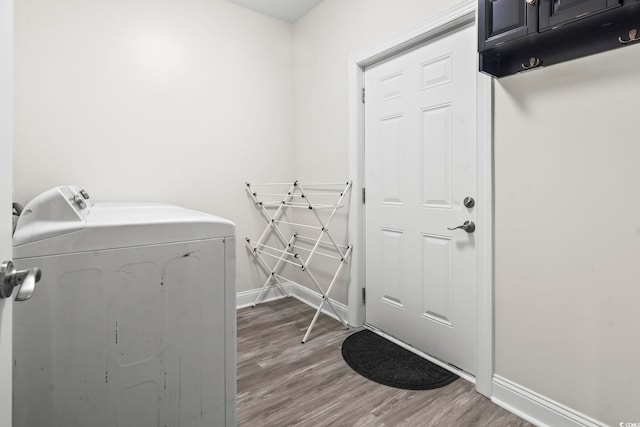 clothes washing area with separate washer and dryer, hardwood / wood-style floors, and cabinets