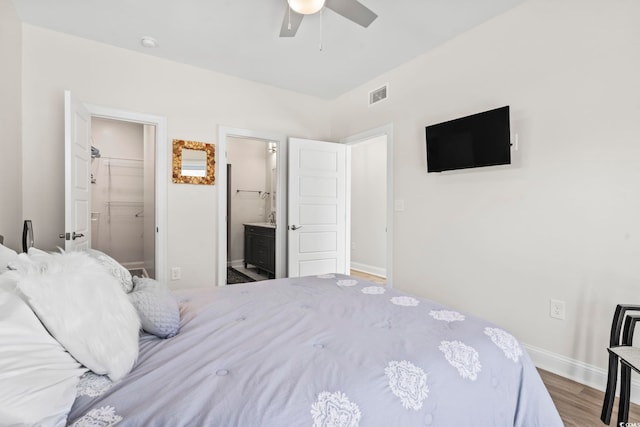 bedroom featuring ensuite bath, a spacious closet, ceiling fan, a closet, and hardwood / wood-style flooring