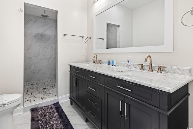 bathroom with a tile shower, vanity, and toilet