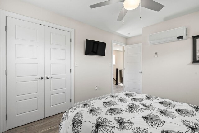 bedroom with hardwood / wood-style flooring, ceiling fan, a wall unit AC, and a closet