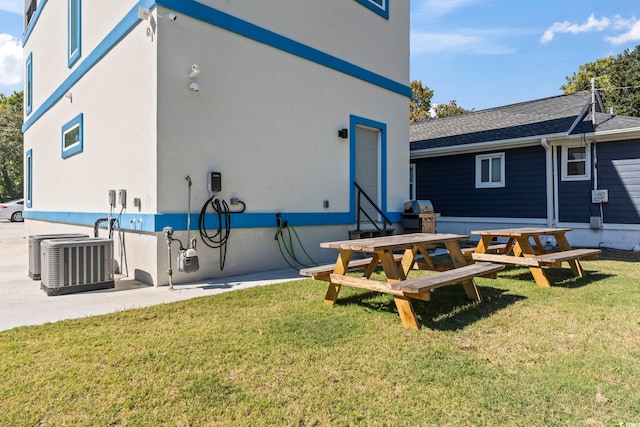 back of property with central air condition unit and a yard