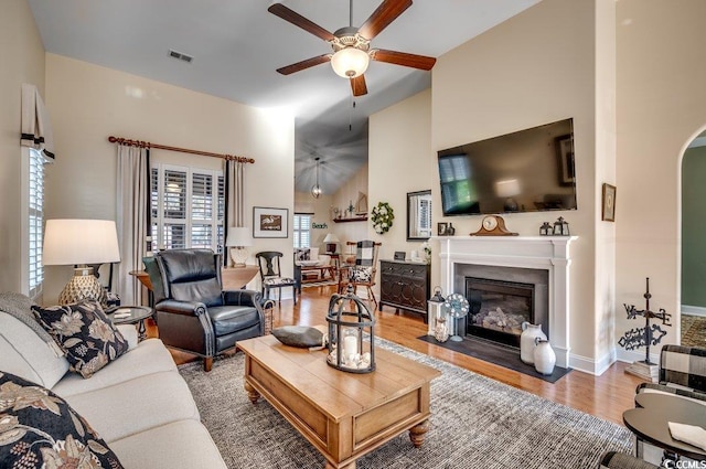 living room with ceiling fan, wood-type flooring, and vaulted ceiling