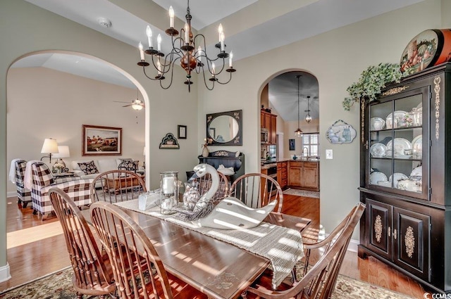 dining room featuring lofted ceiling, light hardwood / wood-style flooring, and ceiling fan with notable chandelier