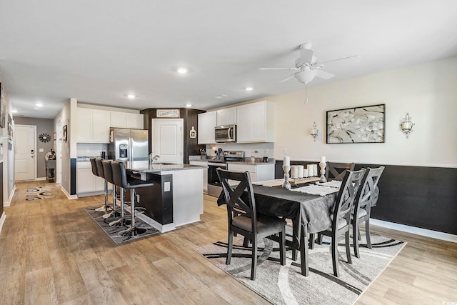 dining area featuring light hardwood / wood-style floors, ceiling fan, and sink