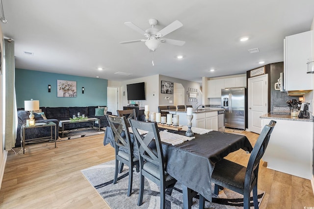 dining room with ceiling fan, sink, and light wood-type flooring