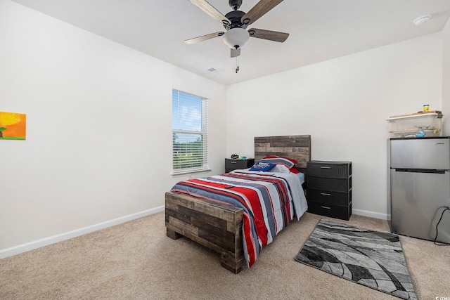 bedroom featuring light colored carpet, stainless steel refrigerator, and ceiling fan