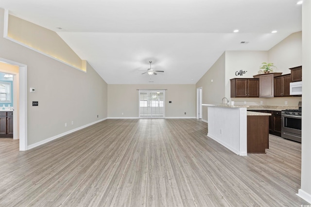 kitchen featuring ceiling fan, stainless steel gas range oven, dark brown cabinets, and light hardwood / wood-style flooring