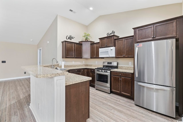 kitchen with dark brown cabinetry, light wood-type flooring, vaulted ceiling, and appliances with stainless steel finishes