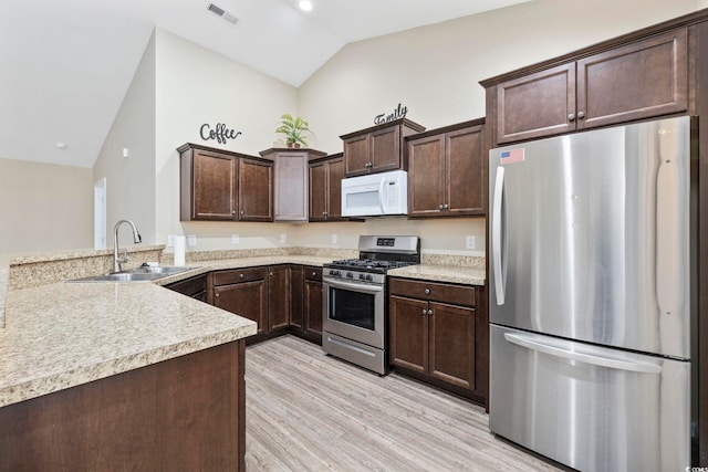 kitchen with sink, vaulted ceiling, dark brown cabinets, kitchen peninsula, and stainless steel appliances