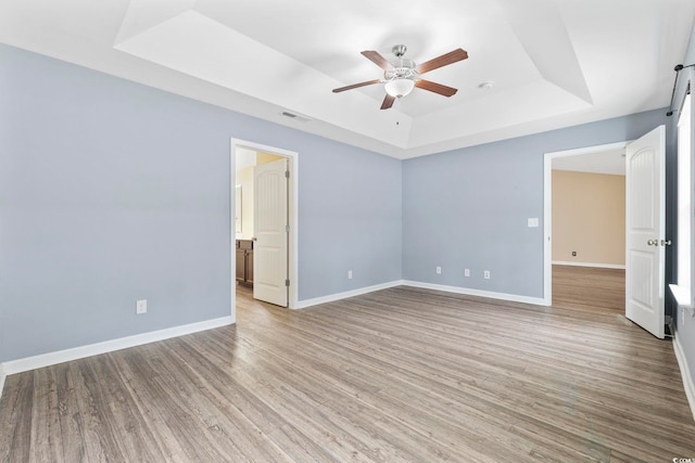 unfurnished bedroom featuring ceiling fan, a raised ceiling, and light hardwood / wood-style flooring