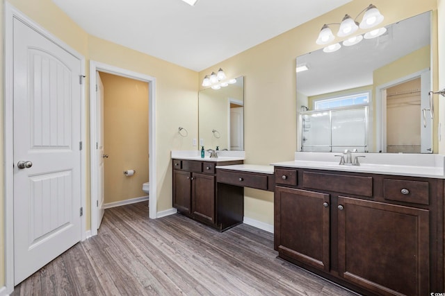 bathroom with wood-type flooring, vanity, toilet, and an enclosed shower