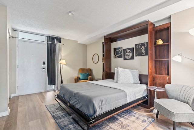 bedroom featuring a textured ceiling and light hardwood / wood-style flooring