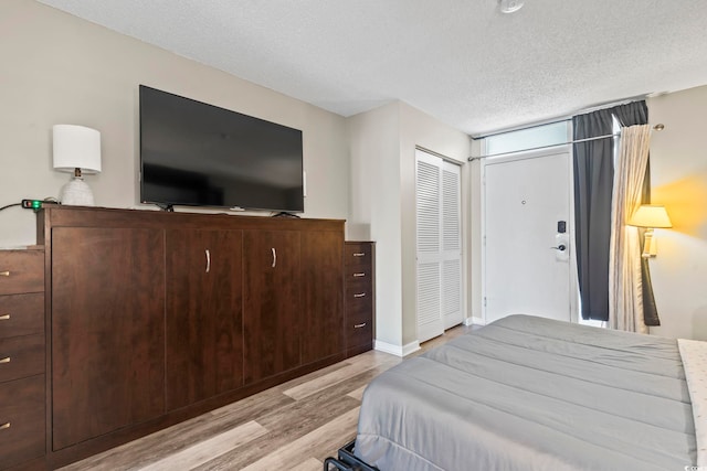 bedroom with a textured ceiling and light hardwood / wood-style flooring