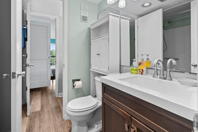 bathroom featuring hardwood / wood-style floors, vanity, toilet, and a textured ceiling