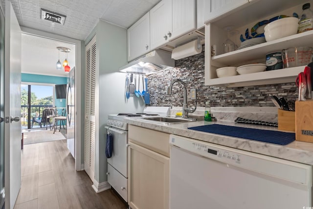 kitchen with tasteful backsplash, white appliances, sink, pendant lighting, and white cabinets