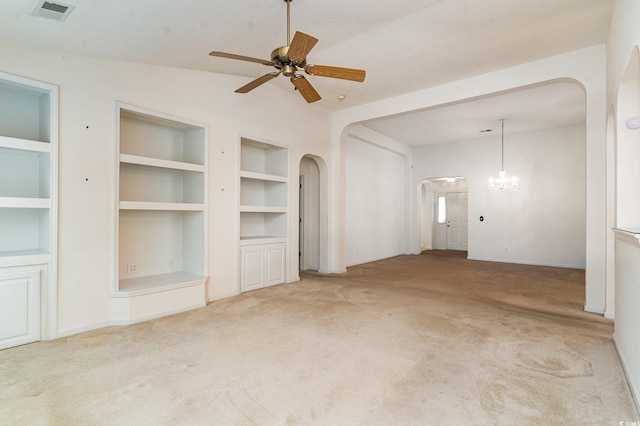 unfurnished living room featuring built in features, a textured ceiling, lofted ceiling, light carpet, and ceiling fan with notable chandelier