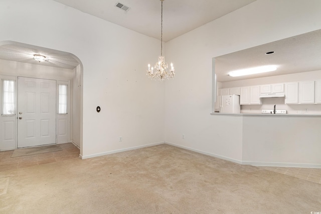 unfurnished dining area with light colored carpet and a chandelier