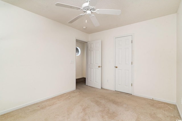 unfurnished bedroom with ceiling fan, light colored carpet, and a textured ceiling