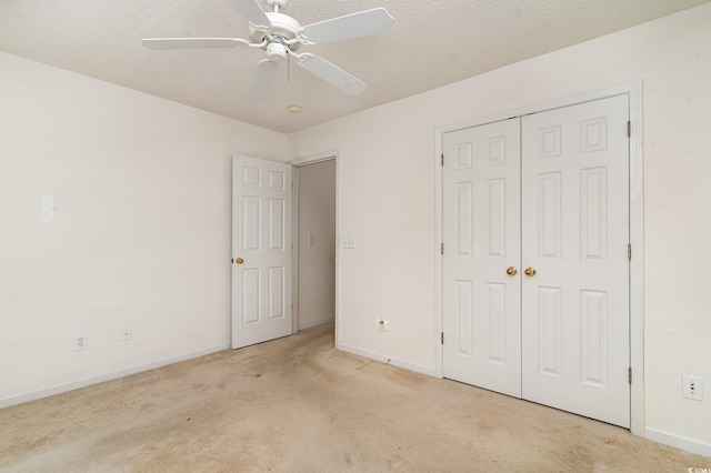 unfurnished bedroom with ceiling fan, light colored carpet, a textured ceiling, and a closet