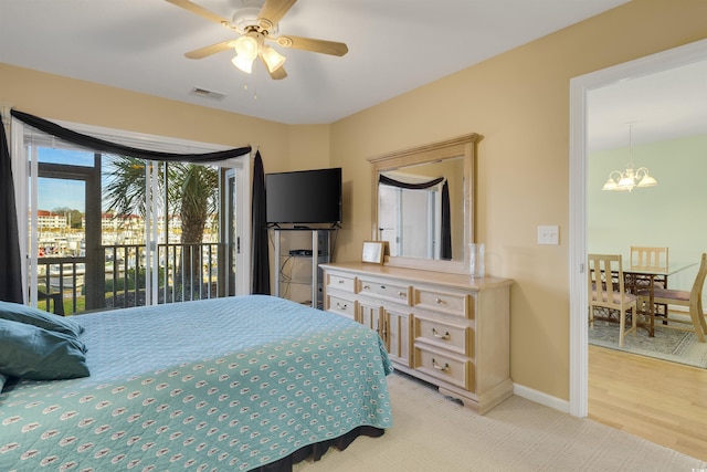 bedroom with ceiling fan with notable chandelier, access to outside, and light hardwood / wood-style flooring