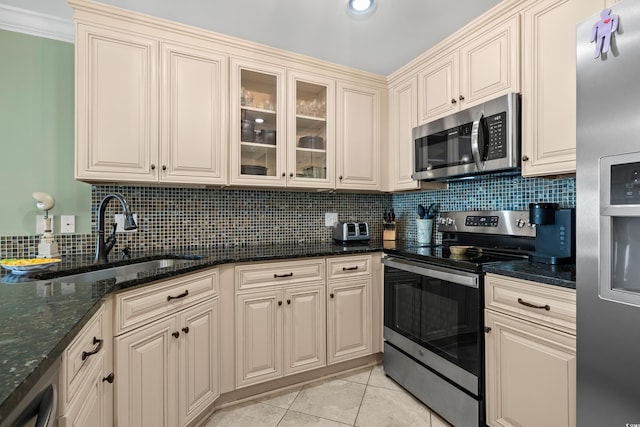 kitchen with dark stone counters, sink, decorative backsplash, light tile patterned floors, and stainless steel appliances