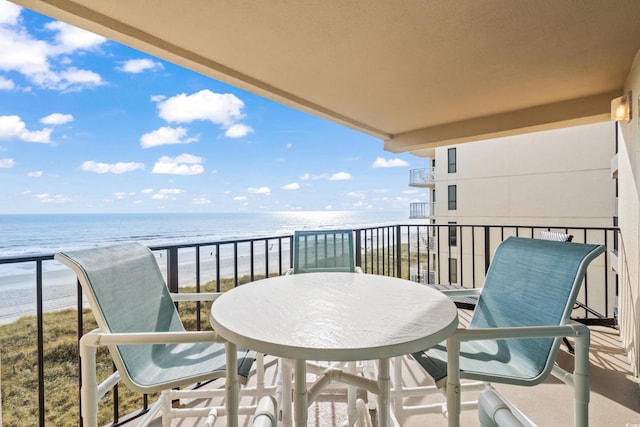 balcony with a water view and a view of the beach