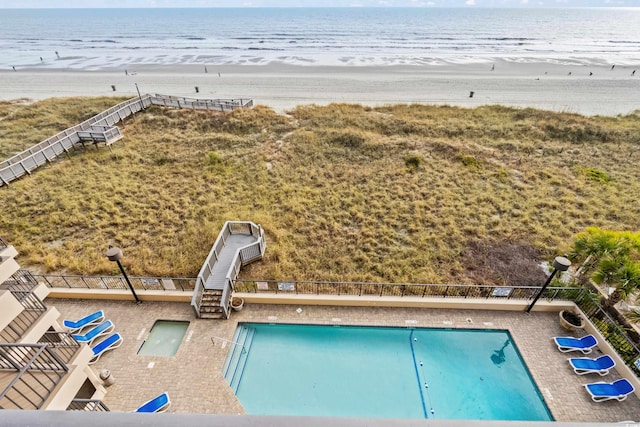 view of swimming pool with a beach view and a water view