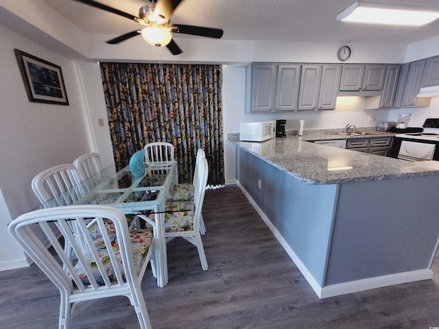 kitchen featuring stone counters, white appliances, kitchen peninsula, and gray cabinetry