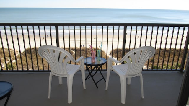 balcony with a water view and a view of the beach