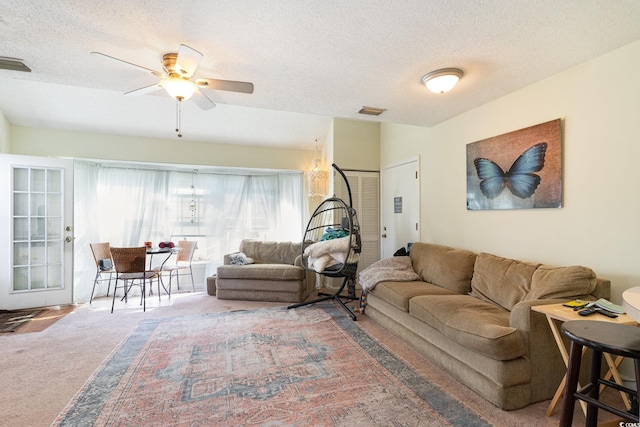 living room featuring ceiling fan, carpet floors, and a textured ceiling