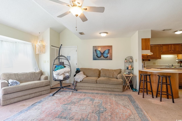 living room featuring light carpet, sink, vaulted ceiling, ceiling fan, and a textured ceiling