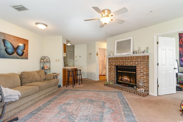 carpeted living room with ceiling fan, a textured ceiling, and a brick fireplace