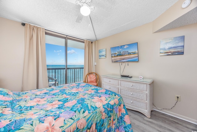 bedroom with floor to ceiling windows, access to outside, ceiling fan, a textured ceiling, and wood-type flooring